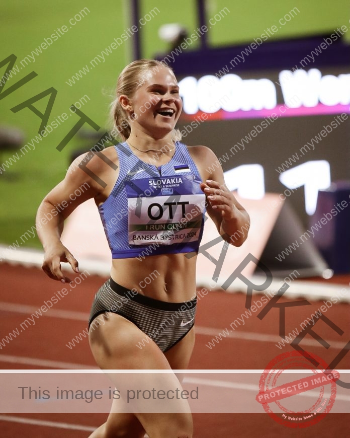 Miia Ott smiles as she finishes a race on the track, wearing a blue top and striped shorts at a Slovakia track meet.
