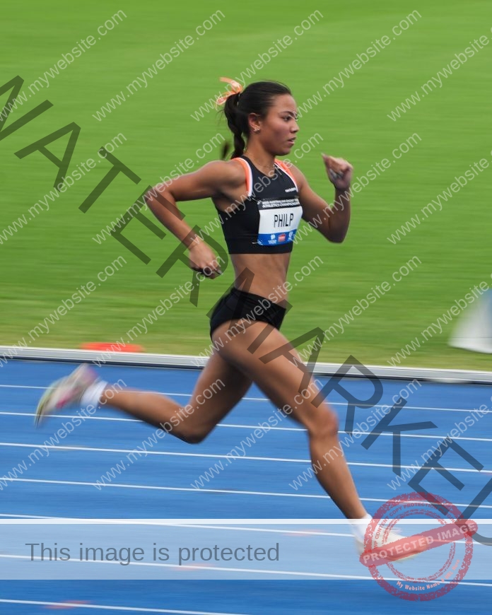 Belle Philp sprints in black uniform on blue track during competitive athletics race.