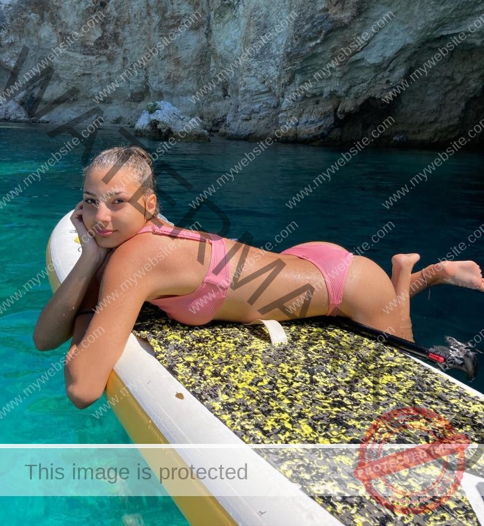 Elisa Enache lounges by the pool on her stomach, wearing a pink bikini.