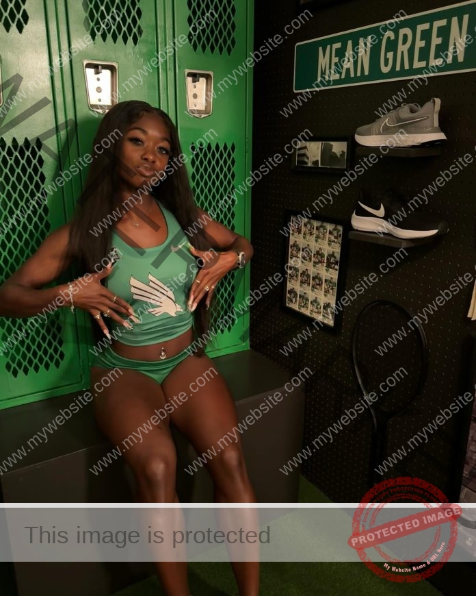 Rayona Runnels posing in the locker room in her green track and field uniform.