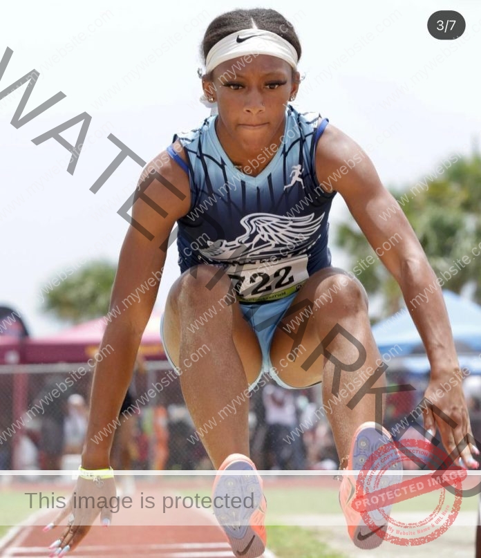 Adina Jackson mid-long jump, competing in a track event.