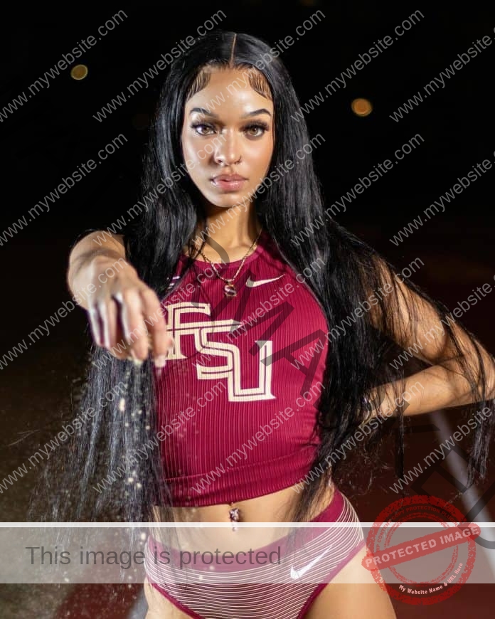 Skyler Reynolds posing in front of a black background for a photo shoot in her FSU track gear, pointing at the camera.