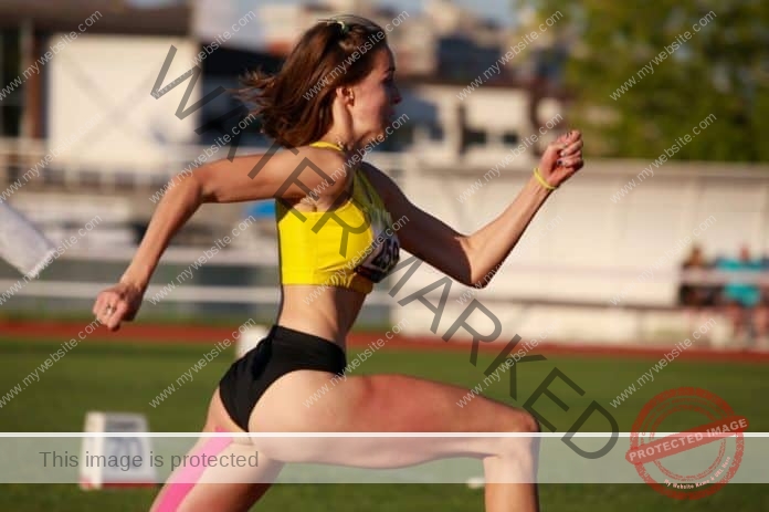 Aleksandrija Mitrovic wearing a bright yellow sports bra and black running tights, sprints as fast as she can in a race.