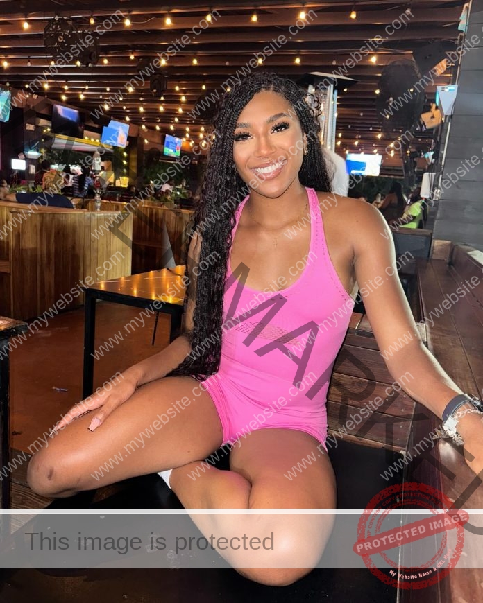 Annika Williams posesin a bar/restaurant in a pink unitard