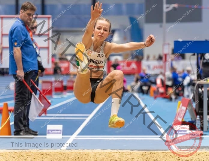 Pola Siewierska mid-air as she attempts a jump into the sand pit.