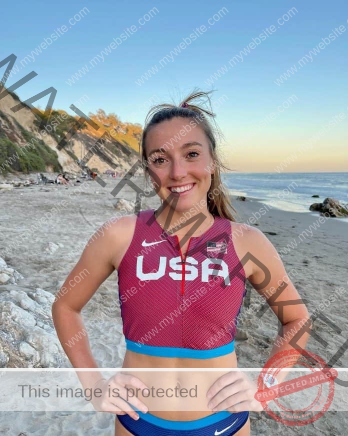 Allie Jones standing on the beach, smiling and wearing a USA track shirt.