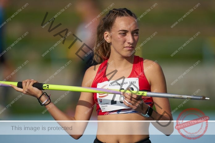 Rebecca Slezáková prepares for a track event, holding a javelin and looking focused.