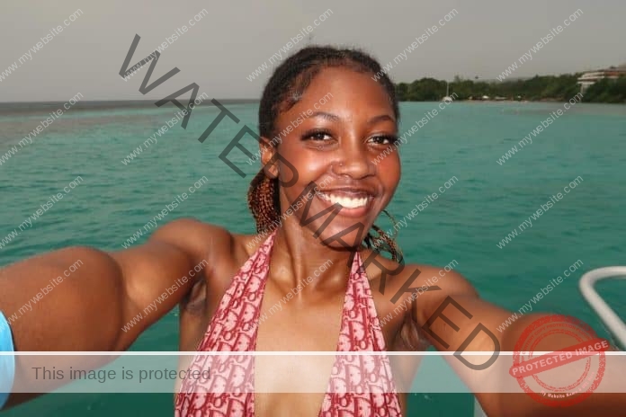 Amber Jamison taking a selfie on a boat, with a huge smile and a one piece bathing suit.