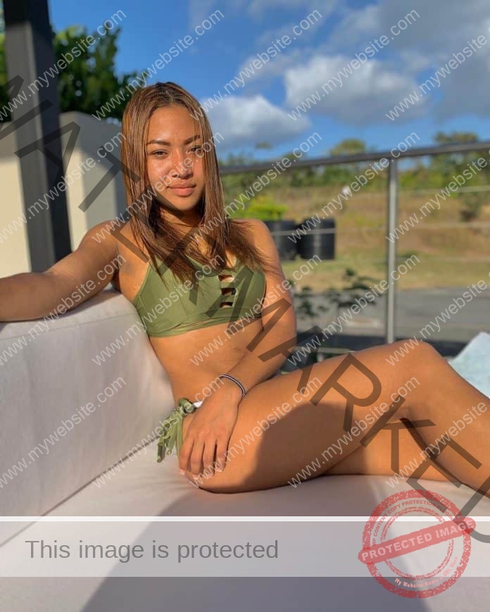 Jennifer Mariangel relaxes by the pool in an army green bathing suit.