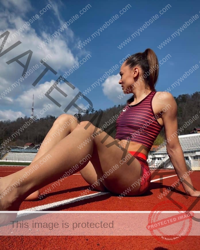 Dana Maria Govoreanu sitting on the track posing with knees up, wearing a sports bra and shorts.