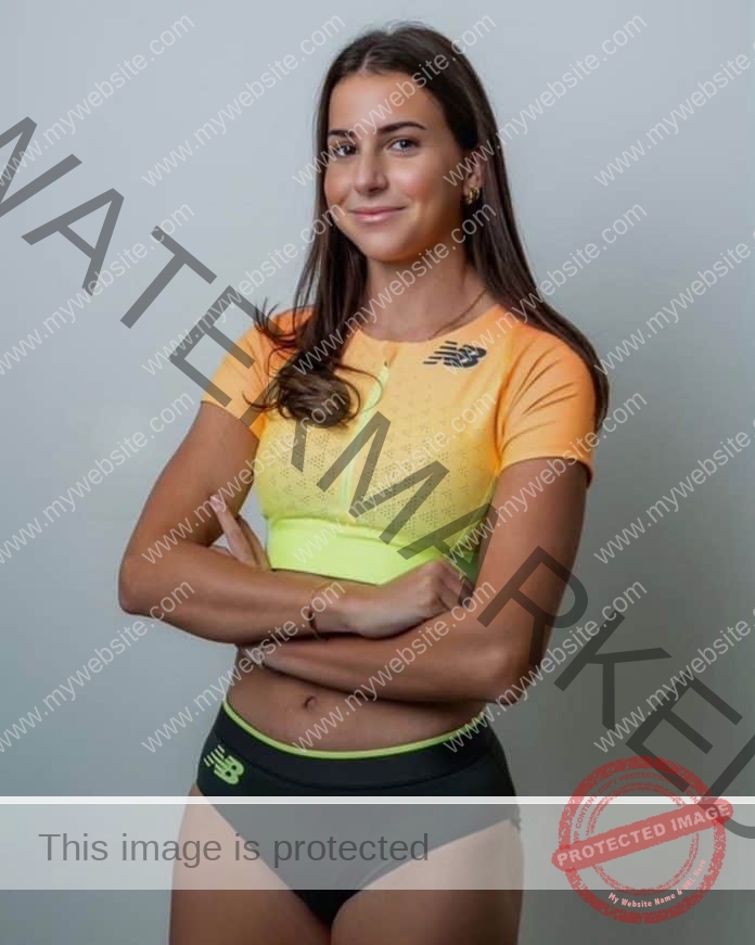 Dawn Amidzovski of Australia posing for a photo in a neon top and black running shorts, arms folded and smiling.