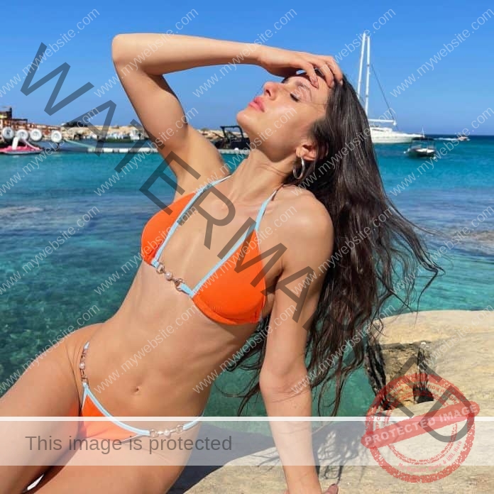 Despoina Charalambous poses on the beach in an orange bikini