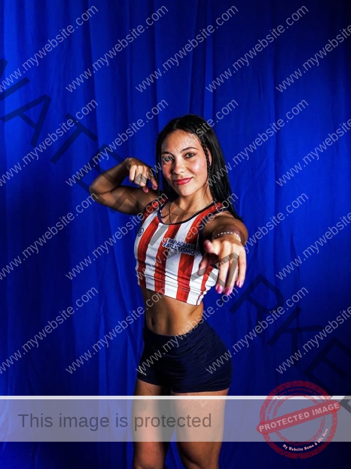 Athlete in red and white striped crop top posing confidently against blue backdrop.