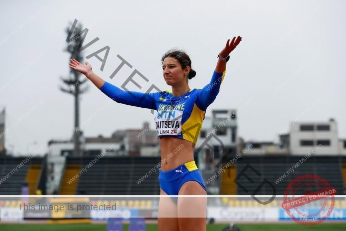 Albina Zaitseva a the track in her track uniform, arms raised, as if she's just won the adoration of the crowd.