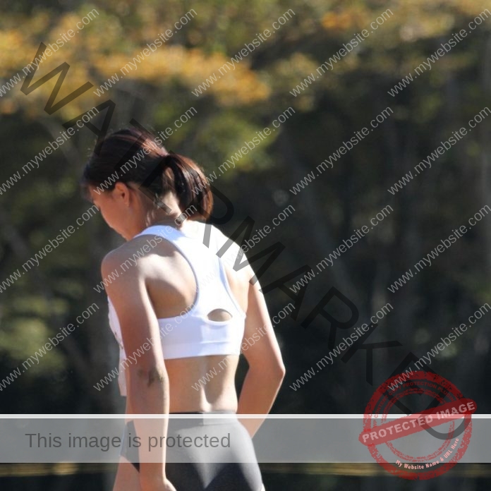 Ayaka Kora os Japan walking on the track at practice, wearing a white sports bra and black shorts.