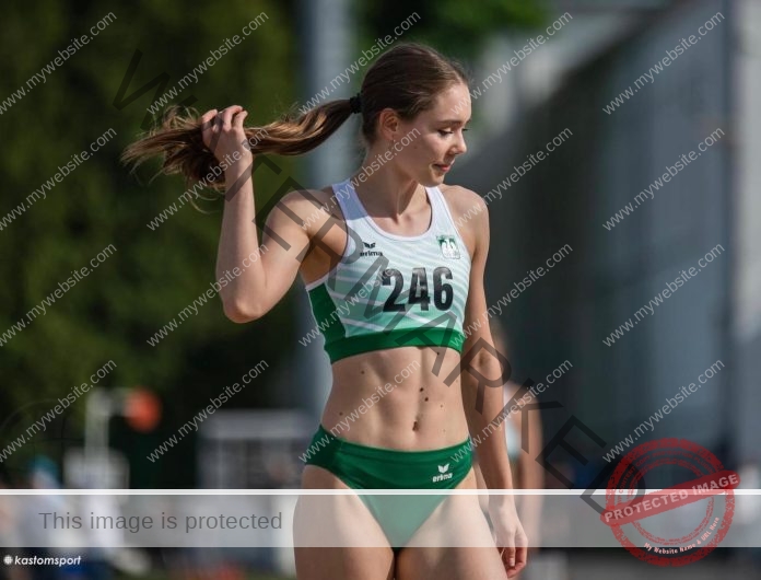 Basia Kostrzewska wearing her track uniform before a race, number 246, playing with her pony tail