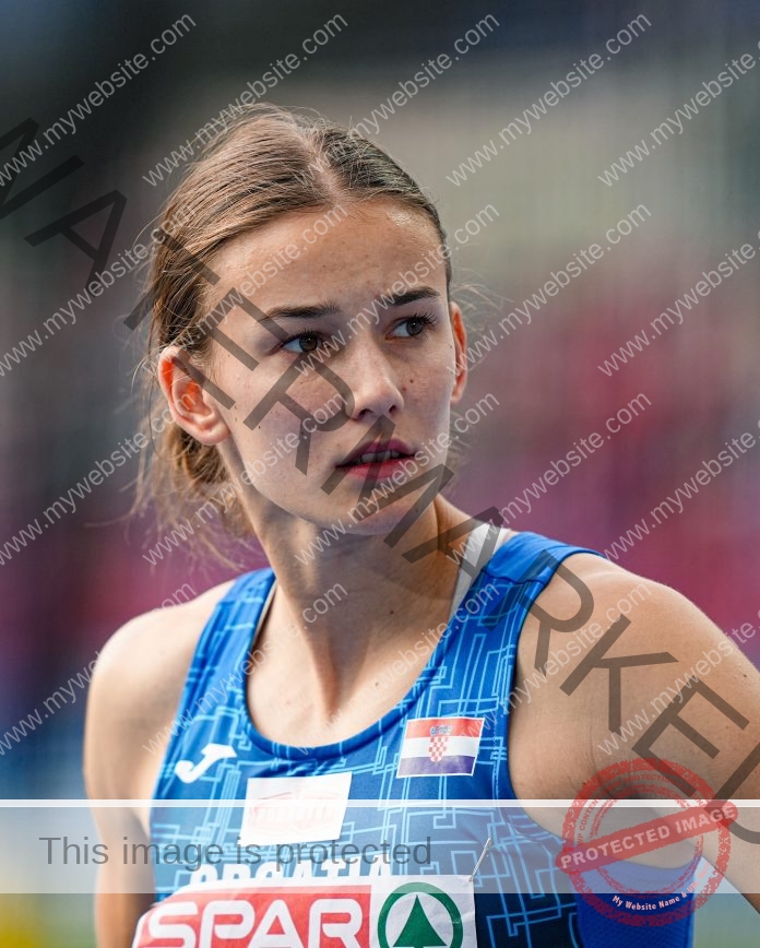 Jana Koščak of Croatia stands on the track focused on her race, wearing a track uniform for Croatia.