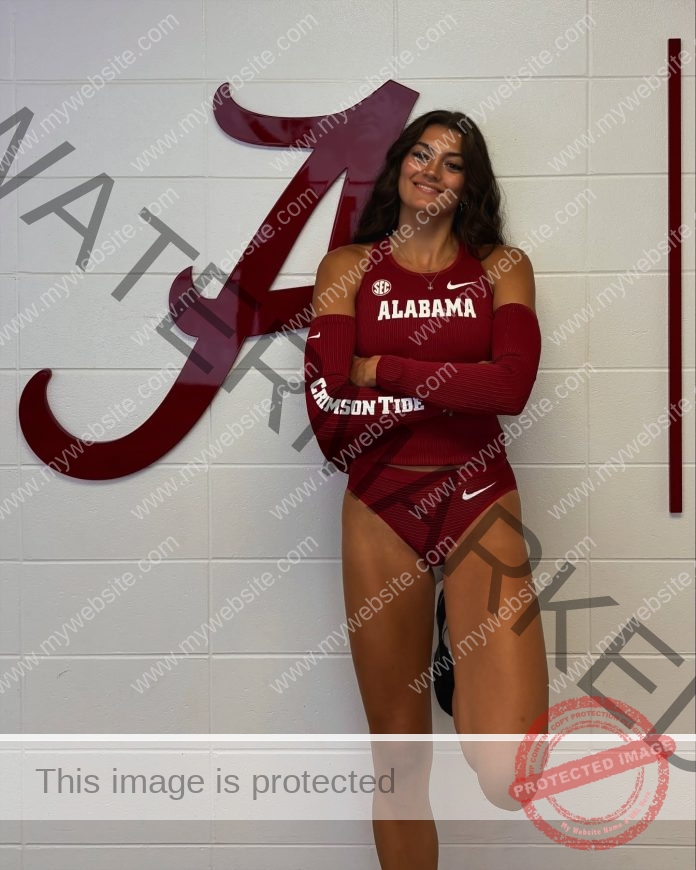 Katelyn Adel posing in her track uniform in front of the Alabama "A".