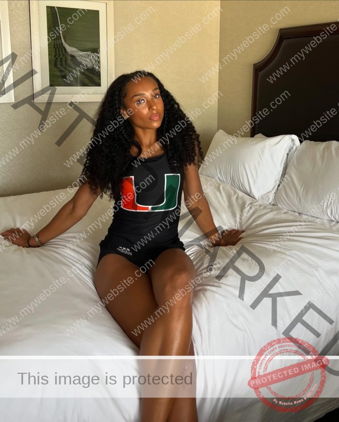 Kennedy Brace sitting on a bed, wearing her Miami track uniform.