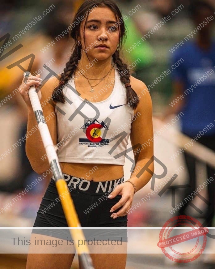 Kourtney Rathke preparing for a pole vault, holding the pole and focused.