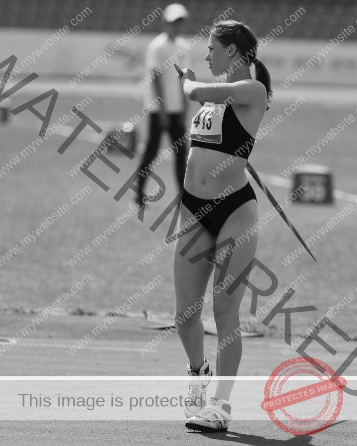 Viktoria Kozhokar in black and white, wearing her competition track uniform and holding a javelin, ready to compete.