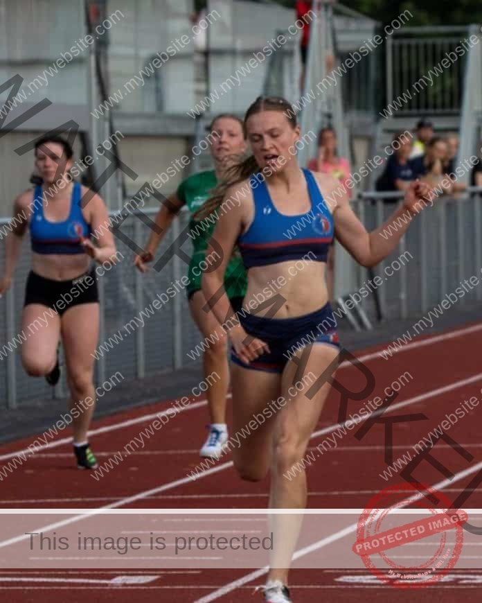 Zelda Eckers running in a race in a blue sports bra and black shorts, leading the pack.