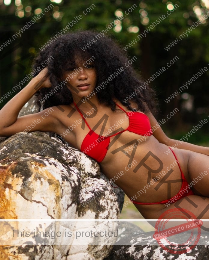 Gloriana Espinoza looking stunning a tight red bikini, posing on the rocks for a picture.