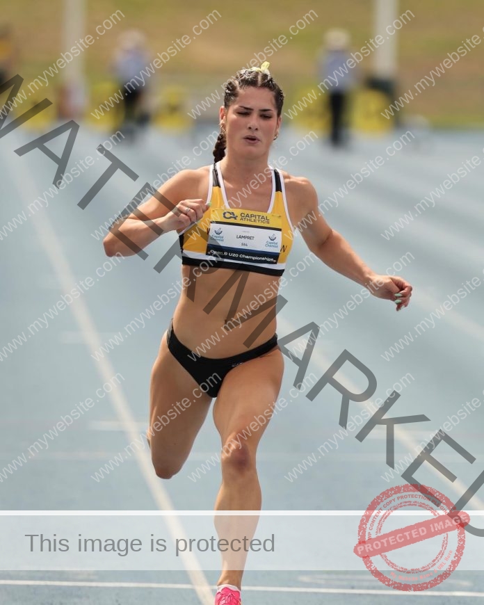 Jasynta Lampret, in a yellow and black uniform, sprints on a blue track with other runners blurred in the background during a race.
