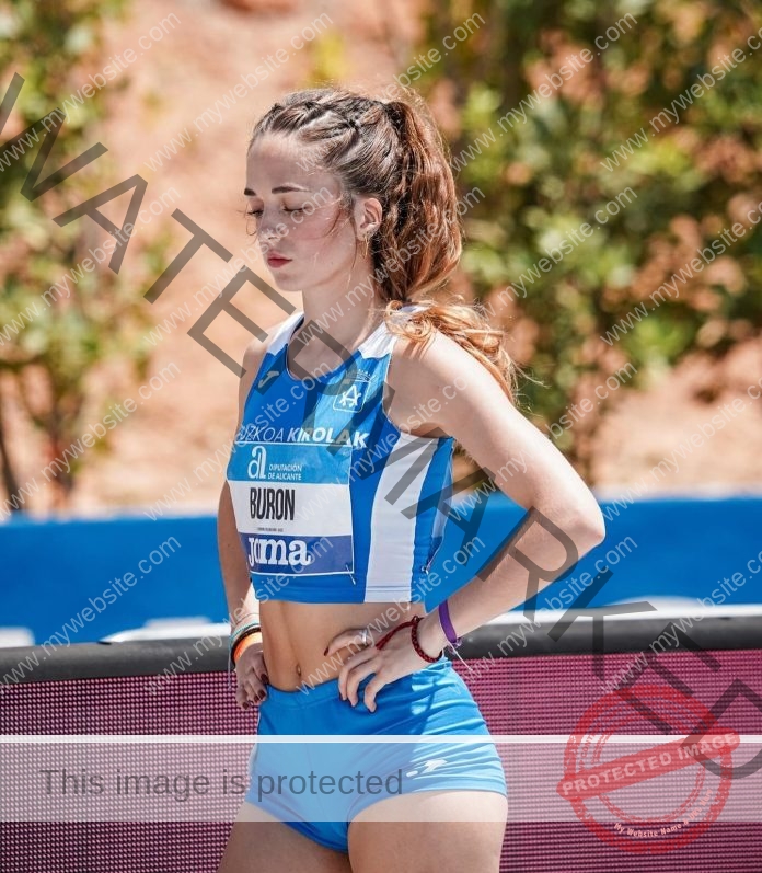 Nora Buron wearing ehr blue track uniform, looking focused on the track before a race.