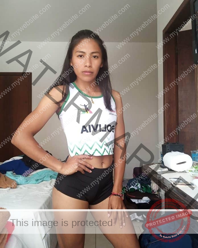 Tania Guasace of Bolivia in a fierce pose in a room, wearing her track uniform top and black shorts.