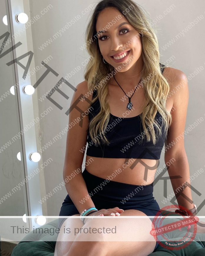 Ana Paula Arguello Del Rio sitting to pose for a picture, wearing a black sports bra and black shorts, smiling big at the camera.