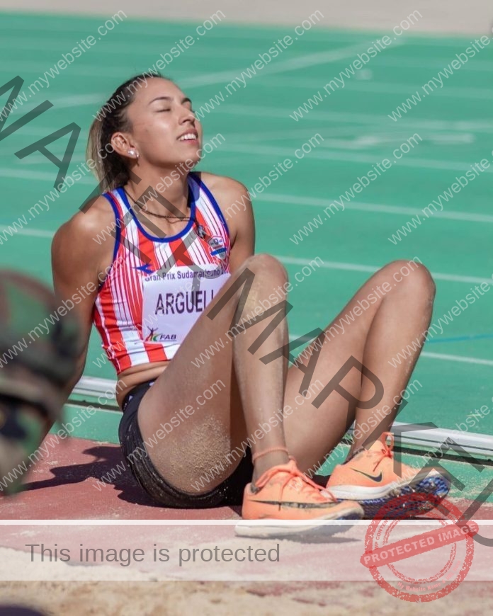 Ana Paula Arguello sits down on the track in her Paraguay national team uniform, exhausted from a race.