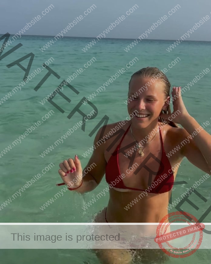 Annika Haldbo smiling waist deep in the ocean, wearing a maroon bikini.