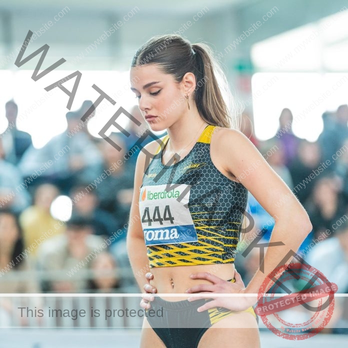 Carla Martitegui focused before competition in yellow and black athletic outfit, number 444 visible.
