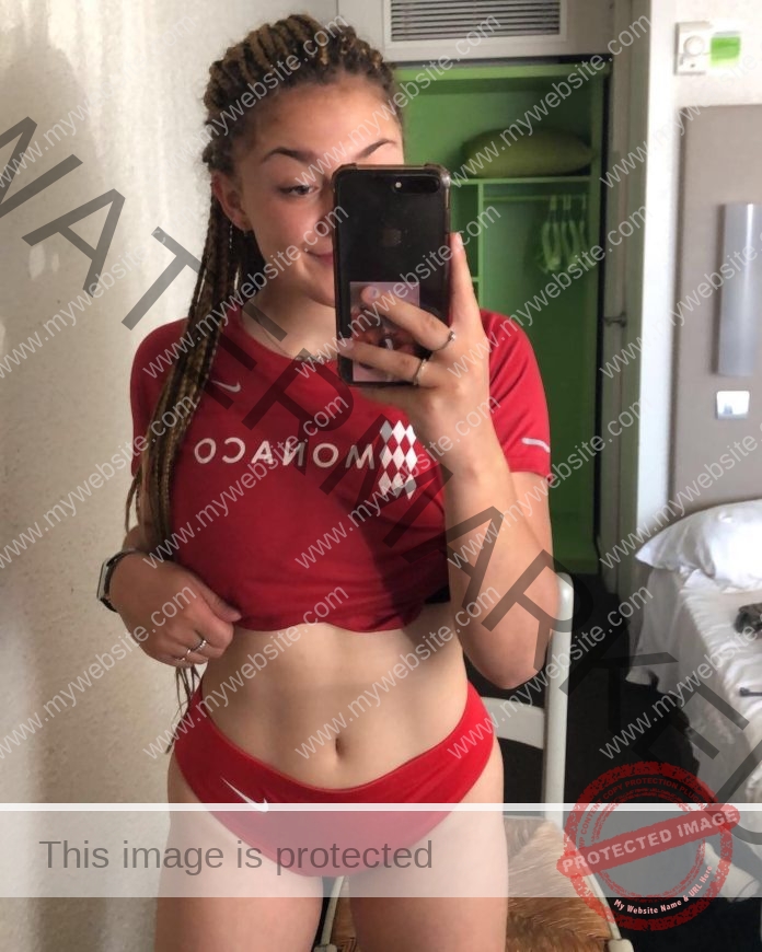 Charlotte Afriat takes a confident mirror selfie wearing a red Monaco athletic top.