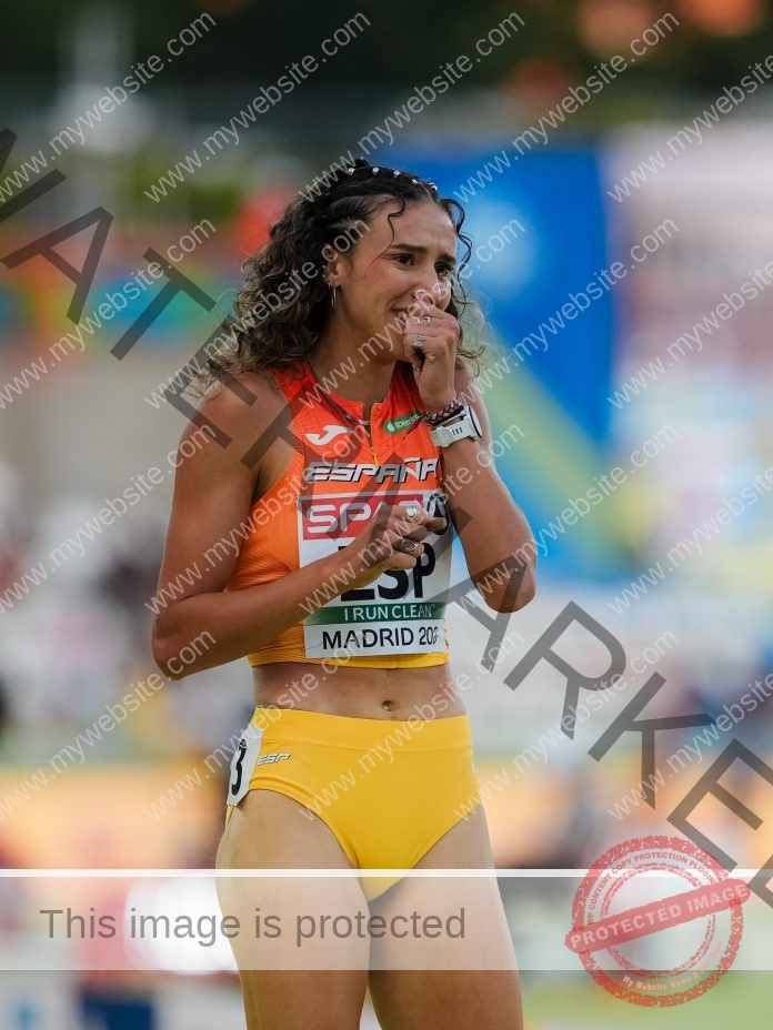 Daniela Fra Palmer, in her yellow orange track outfit of the Spanish national team, puts her hand over her mouth and nose to stifle tears of joy after winning a relay.