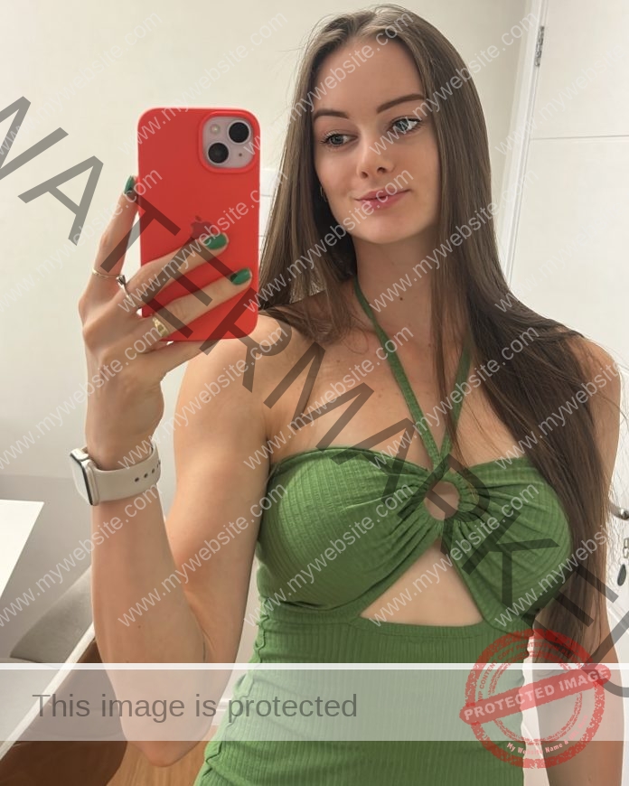 Daniele Campigotto takes a chic mirror selfie in a bright room wearing a green cutout top.