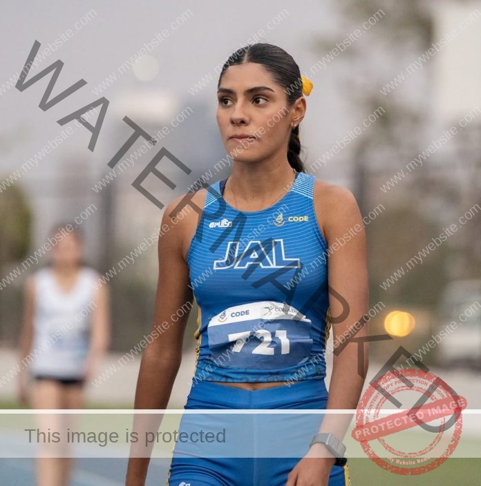 Fatima Vital on the track waiting for a race, with a focused face in her blue track suit.