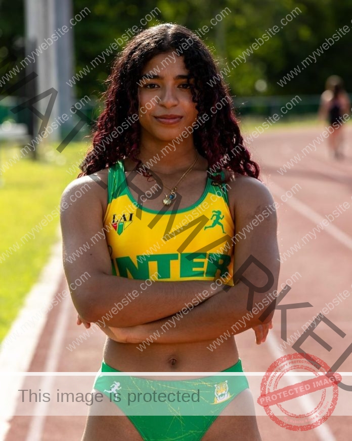 Frances Colon stands confidently on a sunny track in green and yellow INTER uniform.