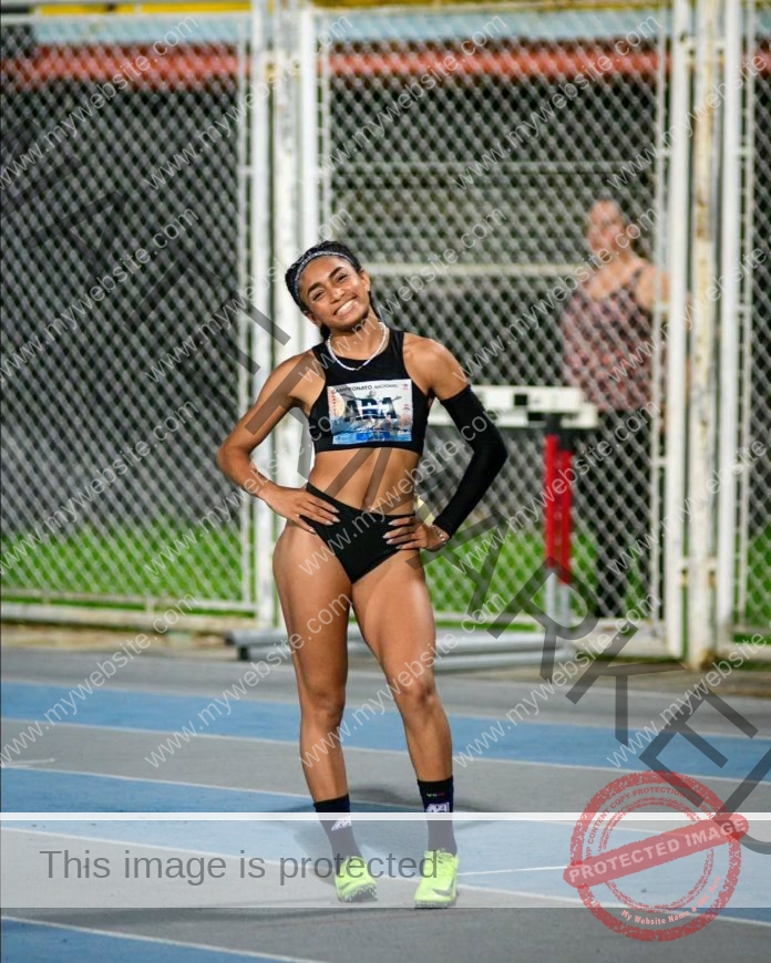 Venezuelan track athlete Ibeyis Romero smiling confidently on the track in black sportswear.