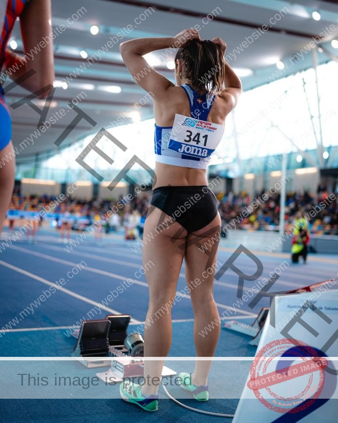 Leire Sainz preparing to sprint on an indoor track, showing focus and athletic determination.