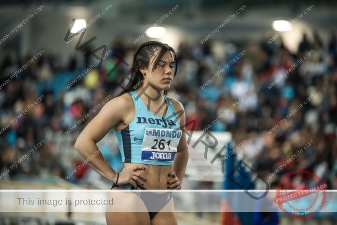 Marta Moreno waits for her race to start with her hands on her hips, wearing her baby blue and dark blue track uniform.