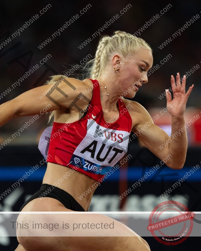 Patricia Brunninger sprinting in red Austria track uniform during indoor athletics event.