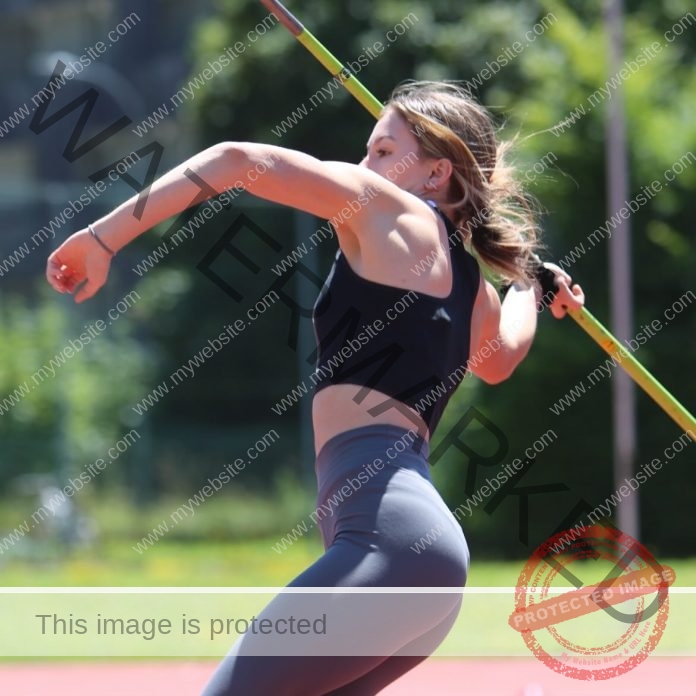 Austrian athlete Tamira Grubbauer throwing javelin with power and precision on a sunny track.