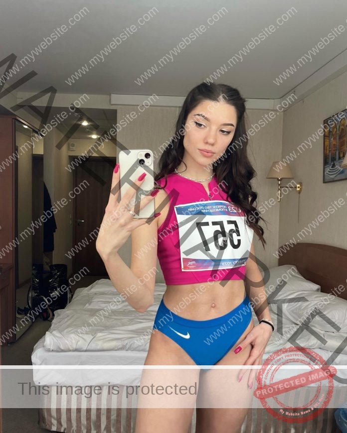 Tayisia Dmitrieva takes a hotel room selfie in her track uniform, hot pink top and royal blue bottoms.