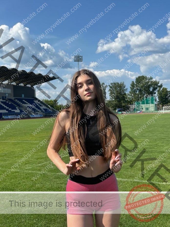 Viktoriya Rusetskaya posing on a sunny stadium field in athletic wear.