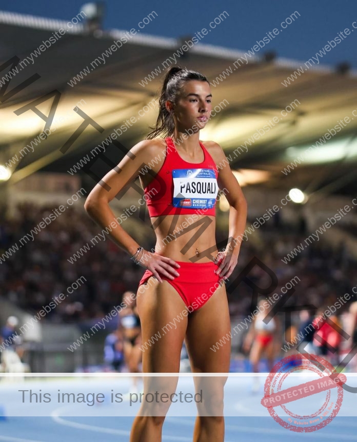 Bella Pasquali in a red track uniform, waiting for a race to start