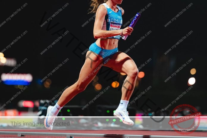 Nora Lamosa running in a track meet with a baton.