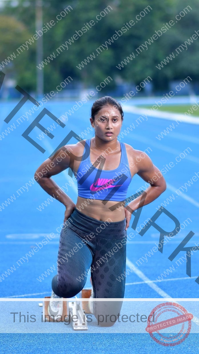 Himashree Roy in blue sports bra stretching on blue running track before training session.
