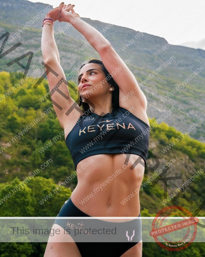 Person stretching outdoors in Keyena athletic wear against a mountainous backdrop.